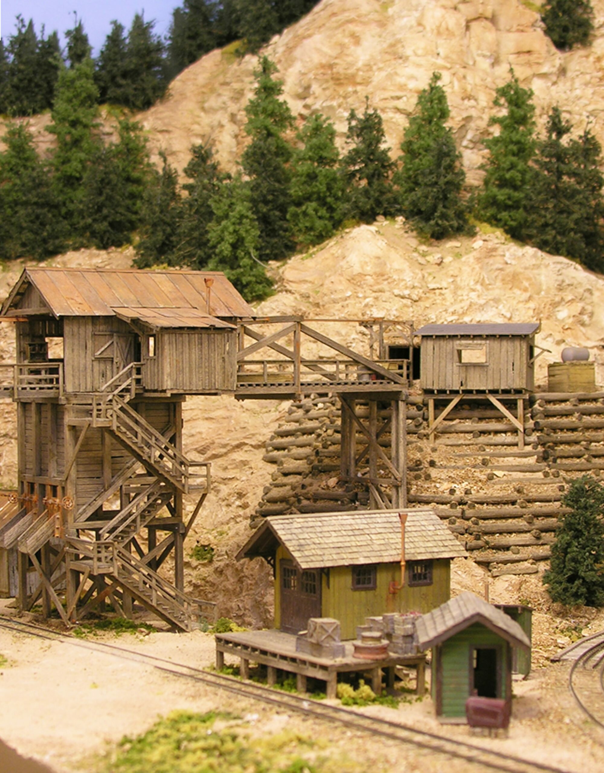 Railroad engine with smoke billowing out of it's stack, on railroad tracks coming towards the viewer.